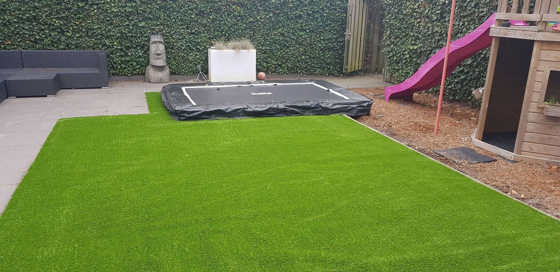 Kleine tuin met kunstgras en een speeltuintje