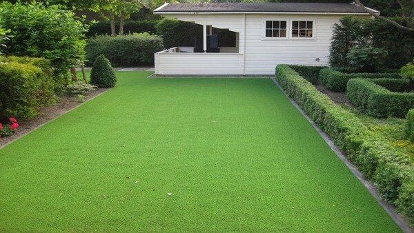 Grote tuin met kunstgras en aan de zijkant heggen