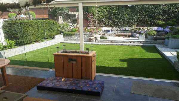 Tuinkamer met uitzicht op de tuin met kunstgras en tegels