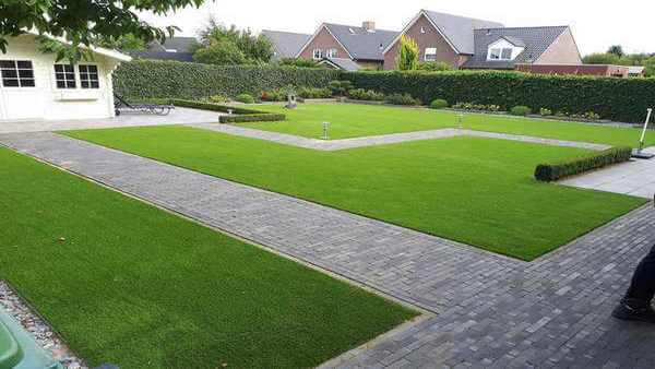 Tuin met paden een wit tuinhuis en daar tussen in kunstgras