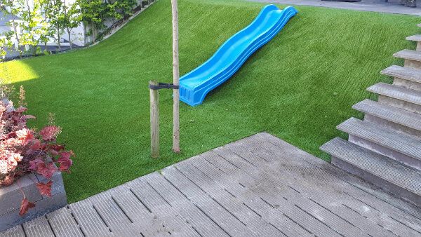 Tuin met kunstgras en een glijbaan