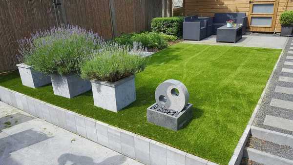 Tuin met kunstgras met vier betonnen tuin afscheidingen